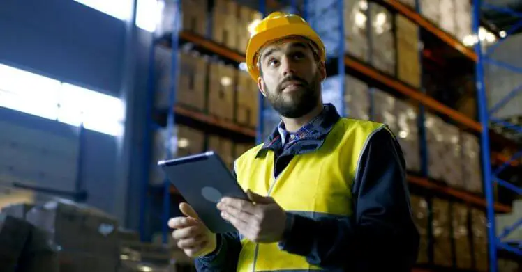 A man in a warehouse using a calculator for CBM