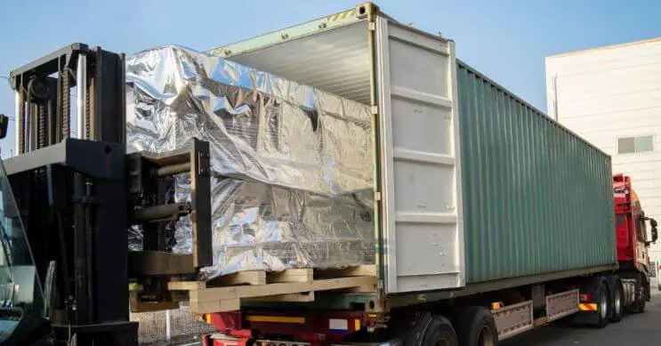 A forklift loads cargo into a container mounted on a trailer, illustrating effective intermodal transport and optimized container load planning.