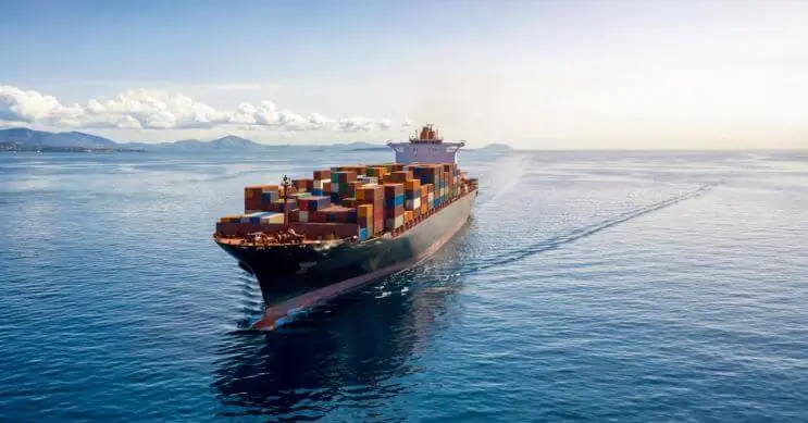 A large container ship carrying a full load of containers, navigating the open sea. This image highlights the importance of Full Container Load (FCL) shipping, where a single shipper exclusively uses an entire container for their cargo, offering advantages like reduced risk of damage and faster transit times.