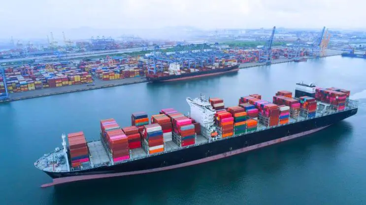 A container ship sailing through the port, emphasizing the role of container load planning in optimizing shipping logistics and reducing costs.