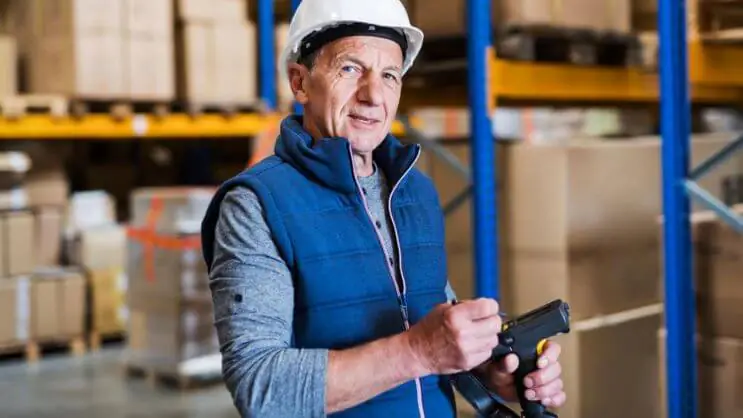 A warehouse worker using a barcode scanner with a digital screen, representing freight rate calculation, shipment tracking, and logistics optimization.